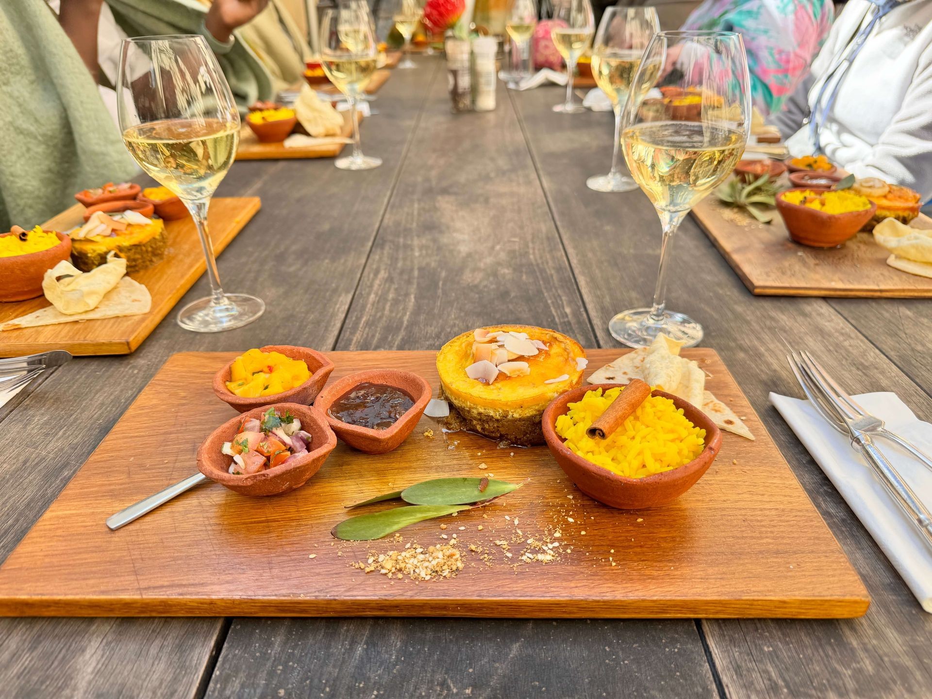 Elegant dining setup with small dishes and wine glasses on a wooden table.